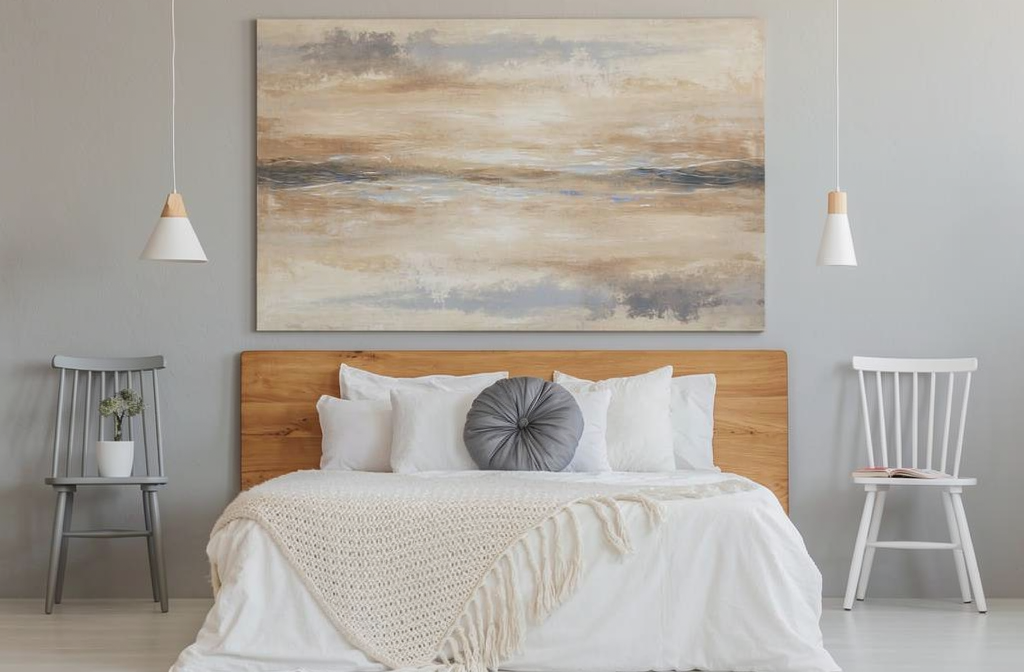 Cuadro abstracto con tonos cálidos beige sobre cama de madera en dormitorio gris moderno